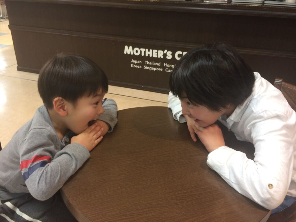 テーブルを挟んで向き合い、笑い合う親子